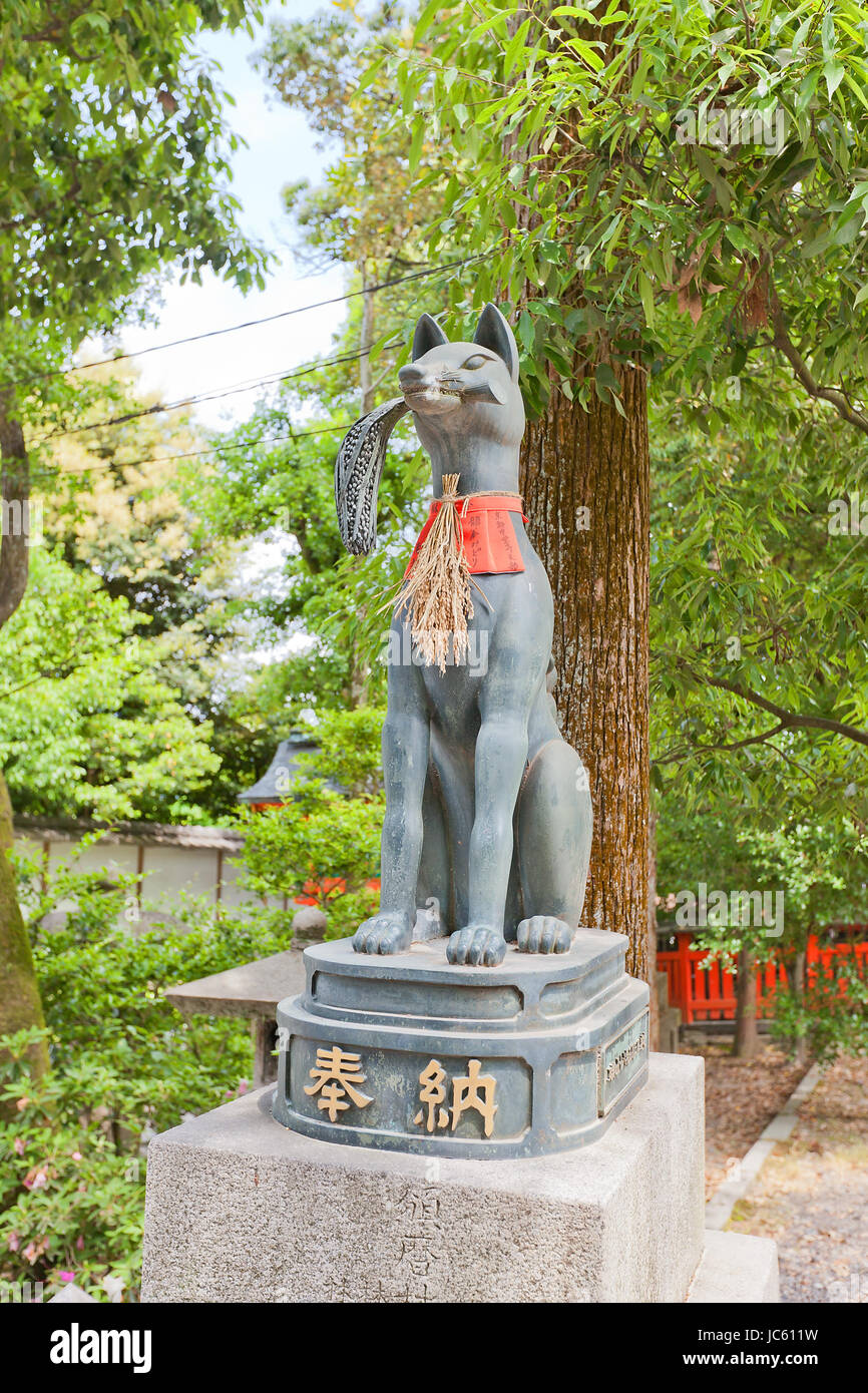 Statue of kitsune with rice sheaf in Fushimi Inari Taisha Shinto Shrine in Kyoto. Kitsune is a fox shapeshifter and a servant of Inari goddess Stock Photo