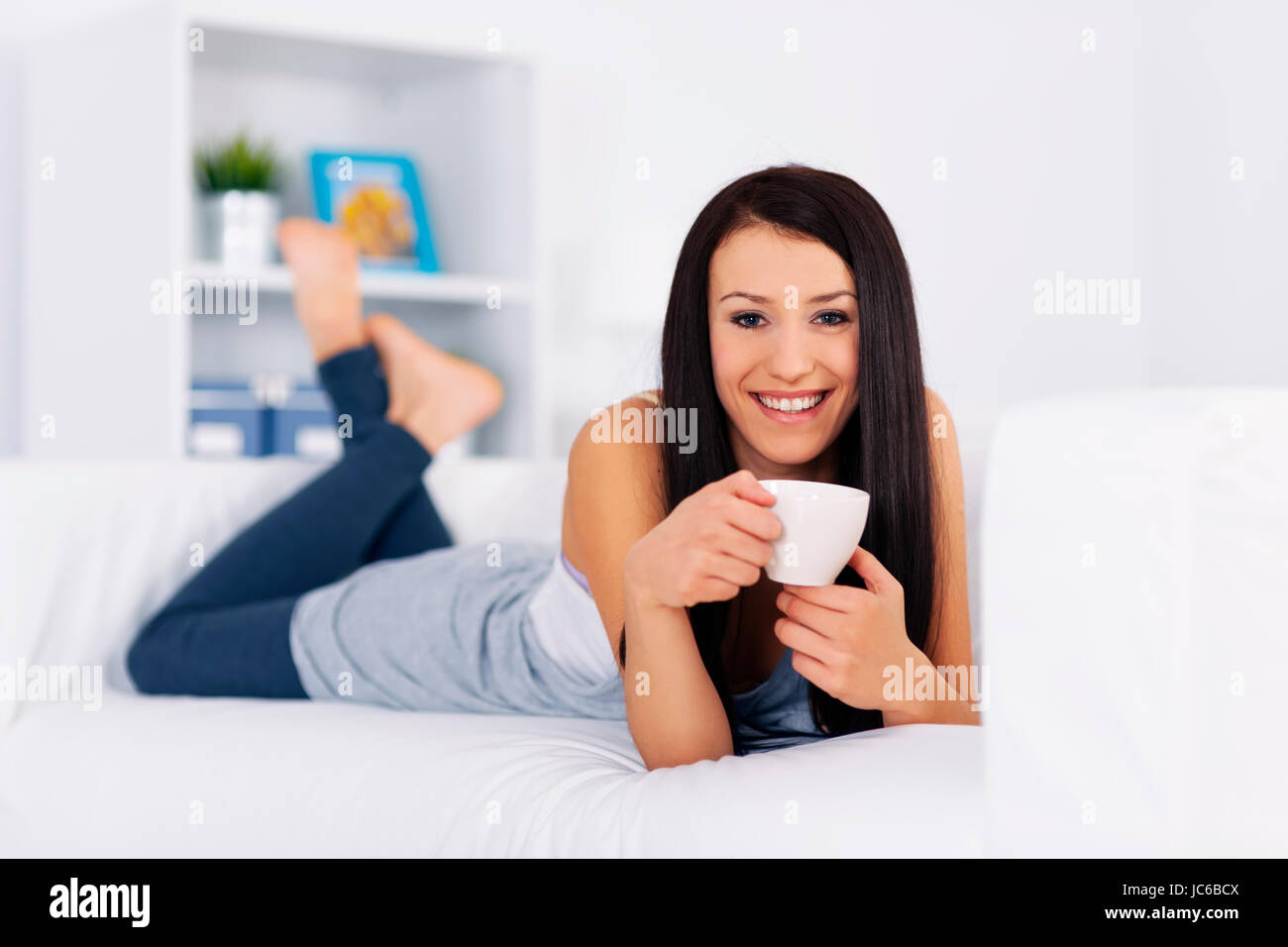 Woman relaxing on couch with cup of coffee Stock Photo - Alamy
