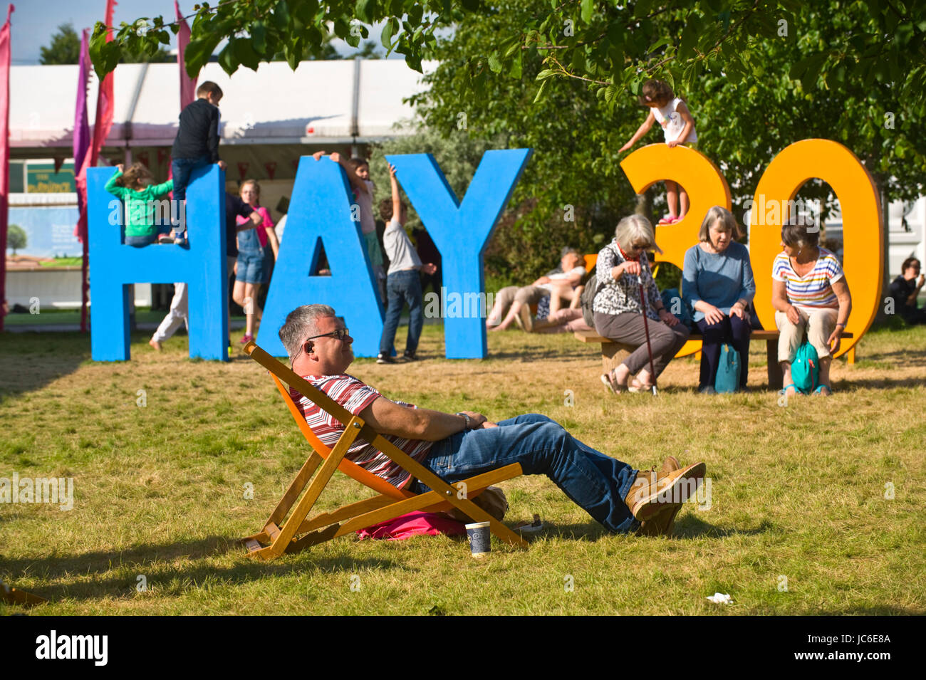 Children playing on Hay 30 sign with man sat in deckchair at Hay Festival 2017 Hay-on-Wye Powys Wales UK Stock Photo