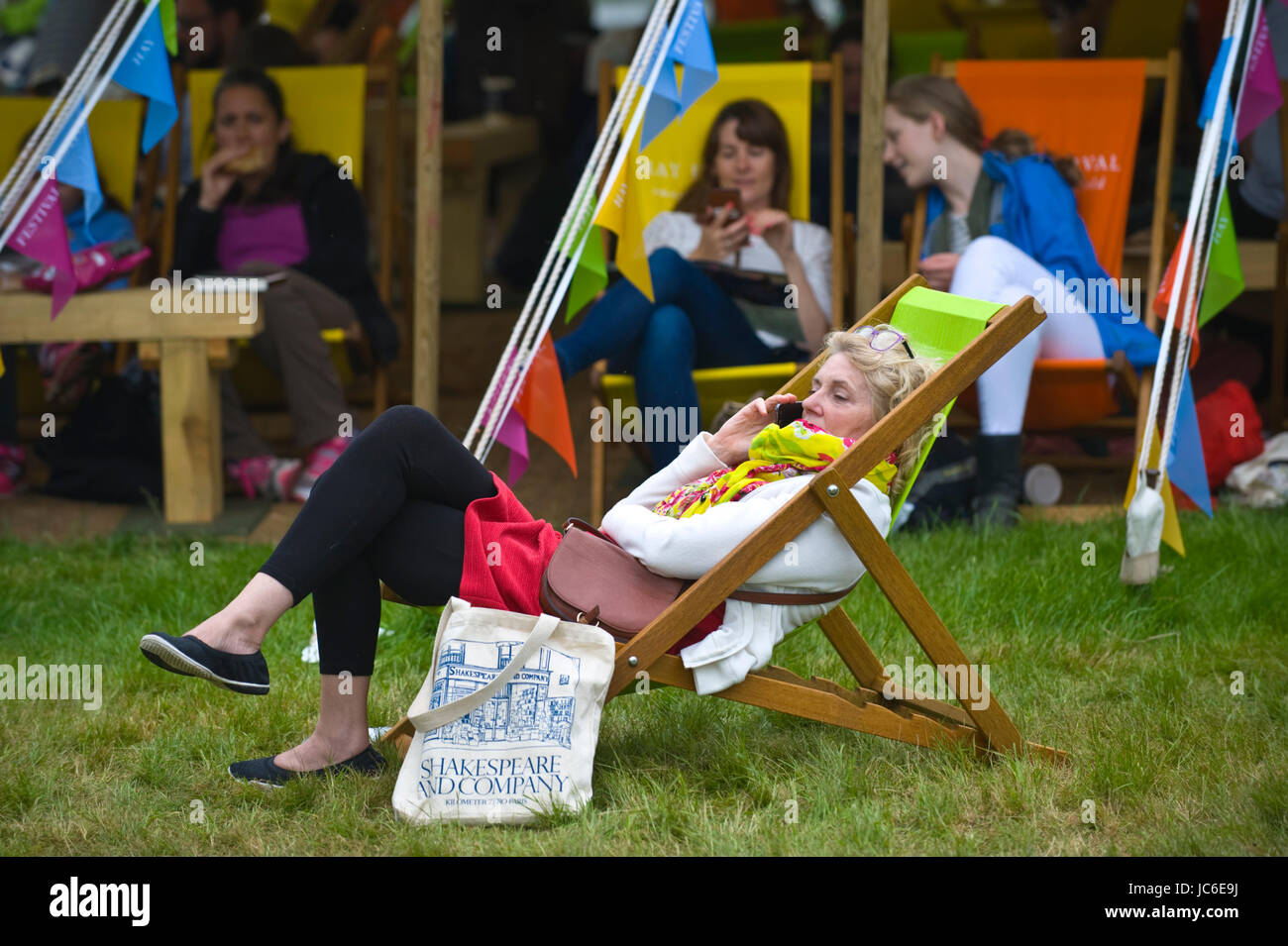 Woman on smartphone & other visitors relaxing in deckchairs at Hay Festival of Literature and the Arts 2017 Hay-on-Wye Powys Wales UK Stock Photo