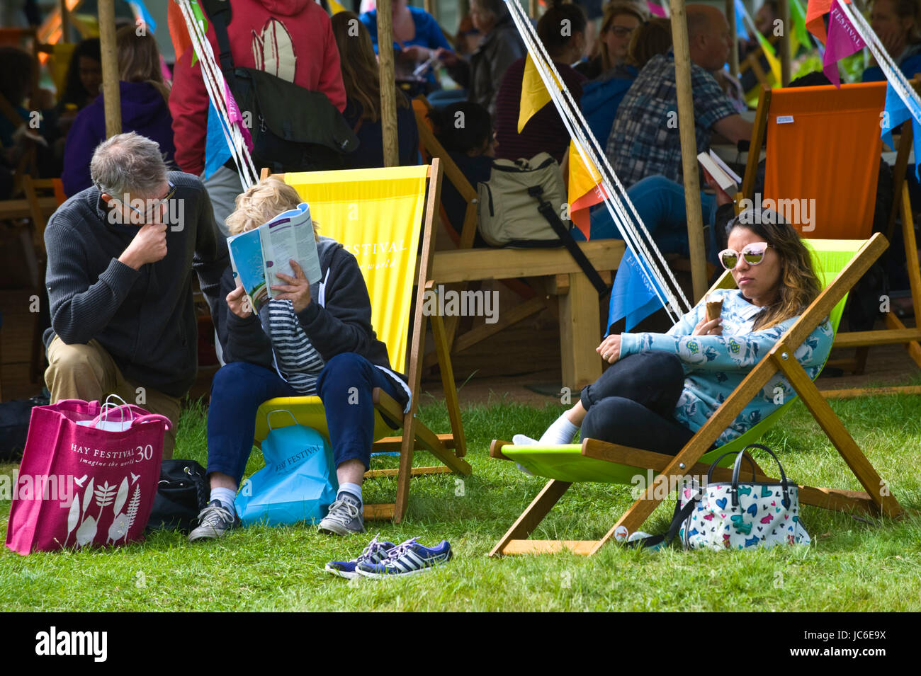 Woman eating ice cream & other visitors relaxing in deckchairs at Hay Festival 2017 Hay-on-Wye Powys Wales UK Stock Photo