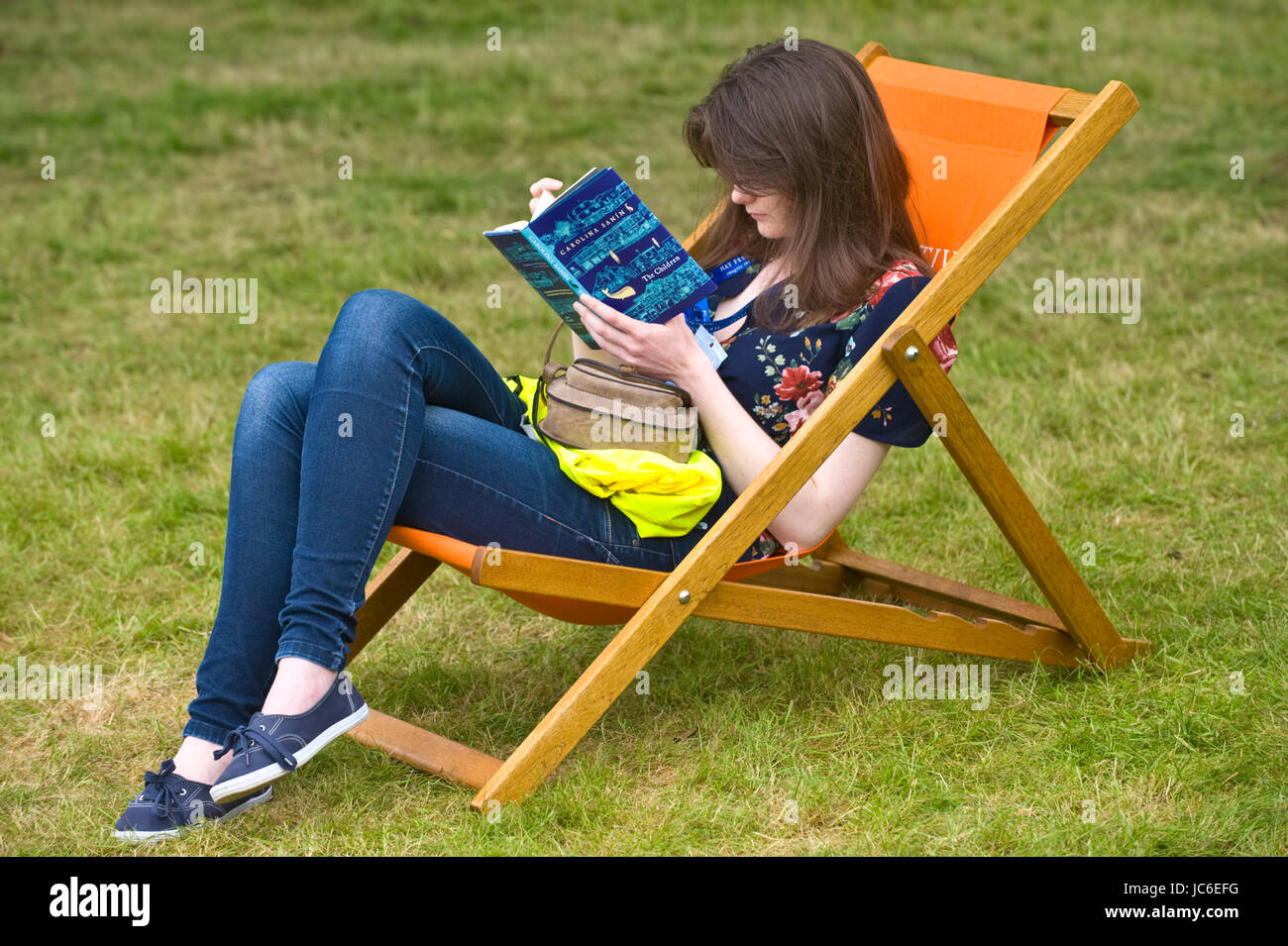 Young woman reading book relaxing in deckchair at Hay Festival of Literature and the Arts 2017 Hay-on-Wye Powys Wales UK Stock Photo