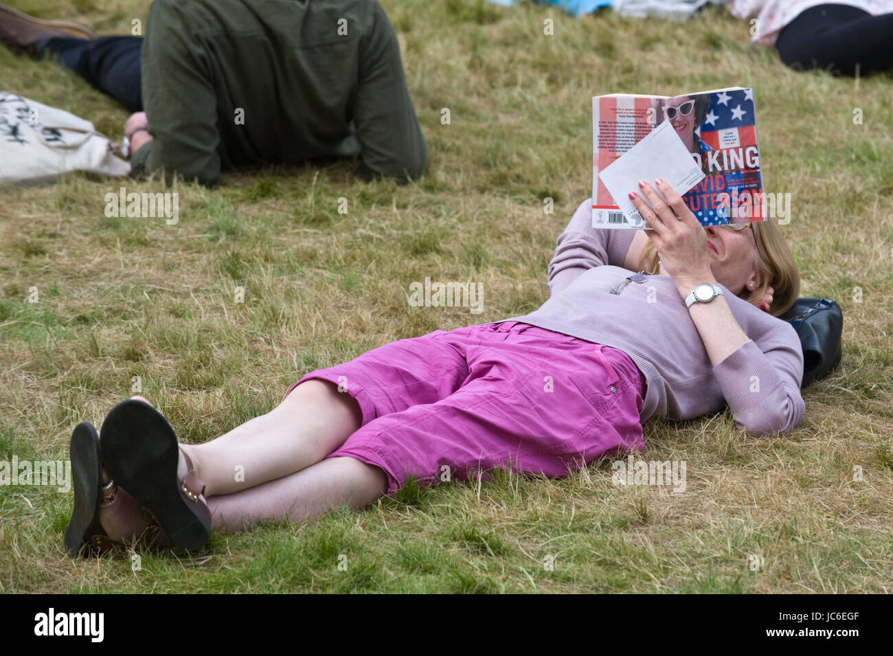 Woman reading book lying on grass relaxing at Hay Festival 2017 Hay-on-Wye Powys Wales UK Stock Photo