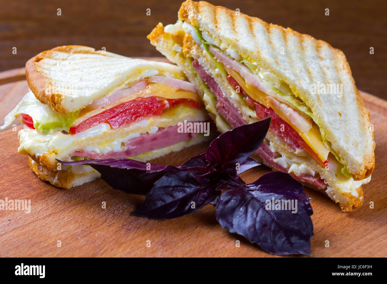 Club sandwiches made with turkey, bacon, ham, tomato, cheese, lettuce and garnished tomatoes. Stock Photo