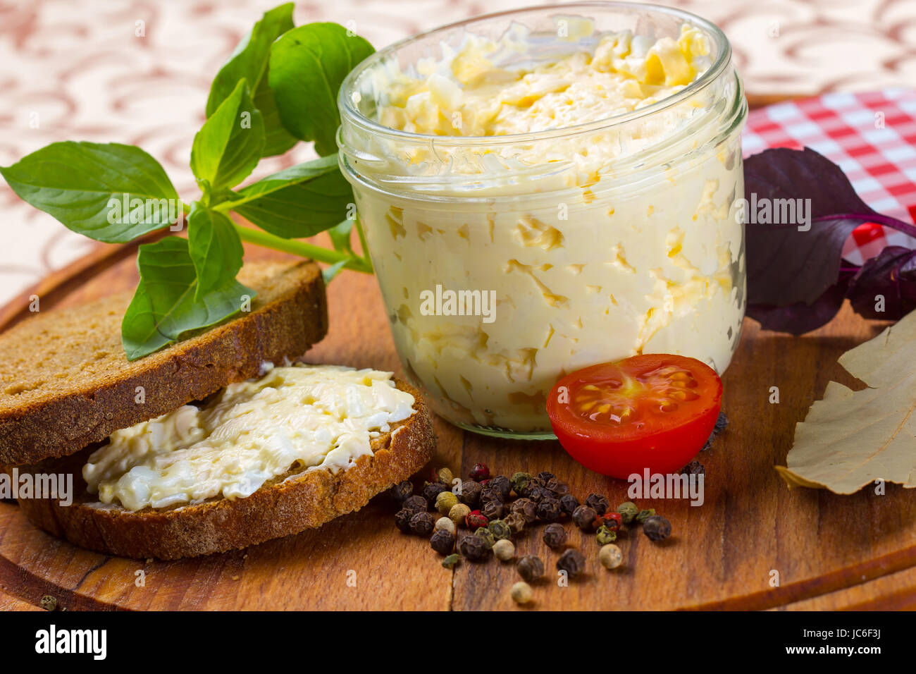 Fresh cream cheese with rye bread, herbs and spices, served on a wooden plate Stock Photo