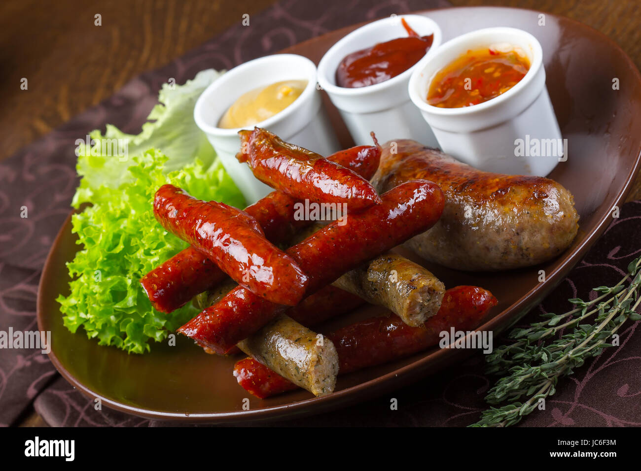Grilled assorted sausages with sauces, salad and rosemary Stock Photo