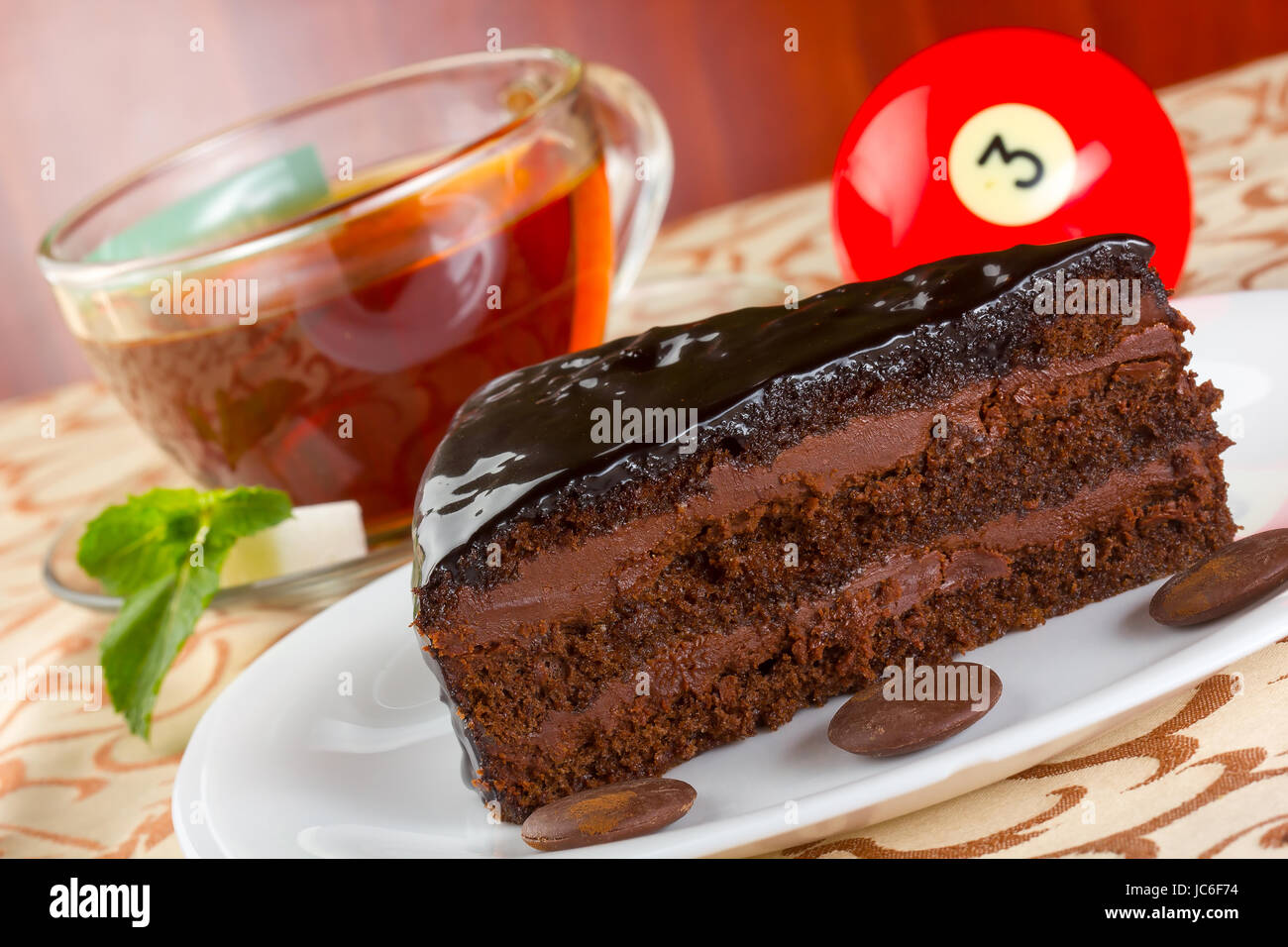Portion of chocolate cake and cup of tea with fresh mint, served on a white plate Stock Photo