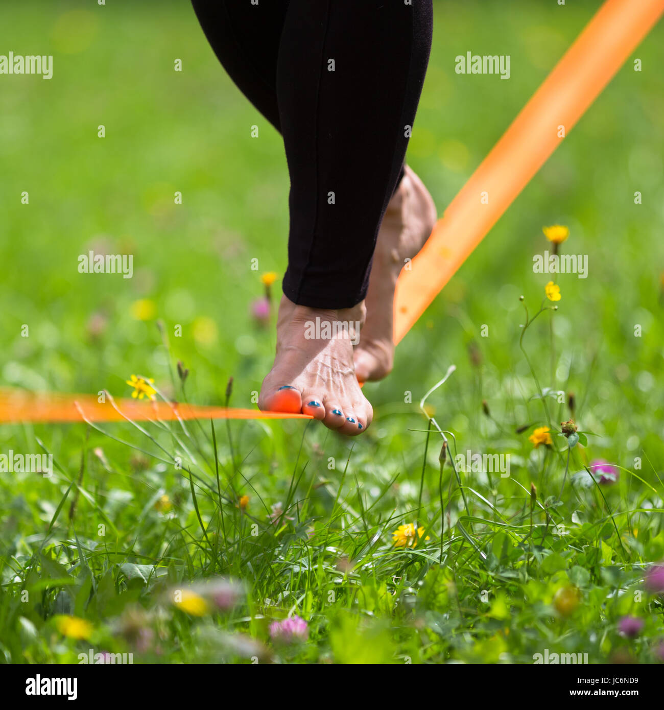 Lady practising slack line in the city park. Slacklining is a practice ...