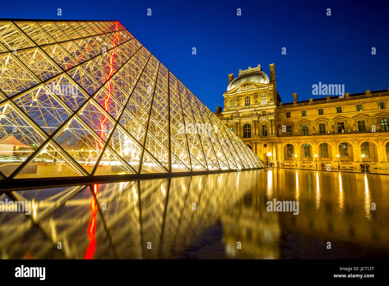 Paris - June 18: Louvre museum at dusk on June 18, 2014 in Paris. This is one of the most popular tourist destinations in France displayed over 60,000 square meters of exhibition space. Stock Photo