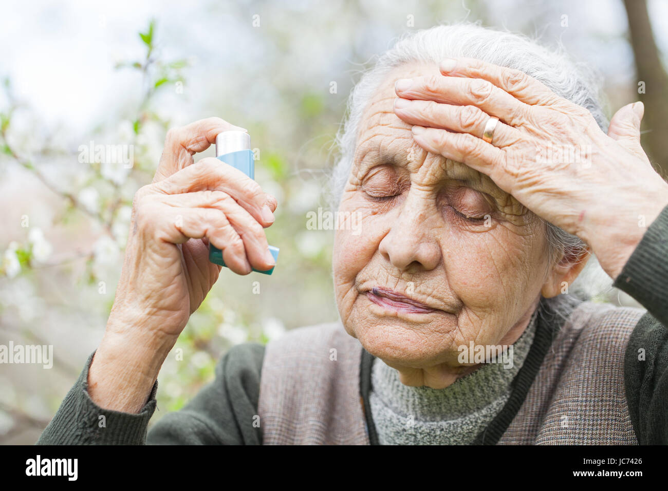 Close up picture of an elderly woman having an asthma attack, holding a bronchodilator Stock Photo