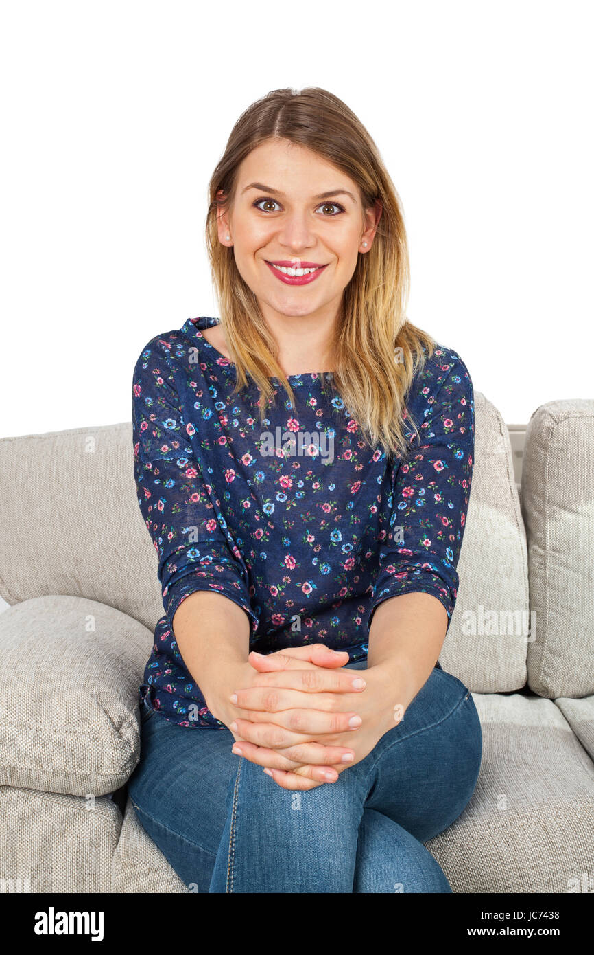 Picture of a smiling young woman sitting on the couch, relaxing at home ...