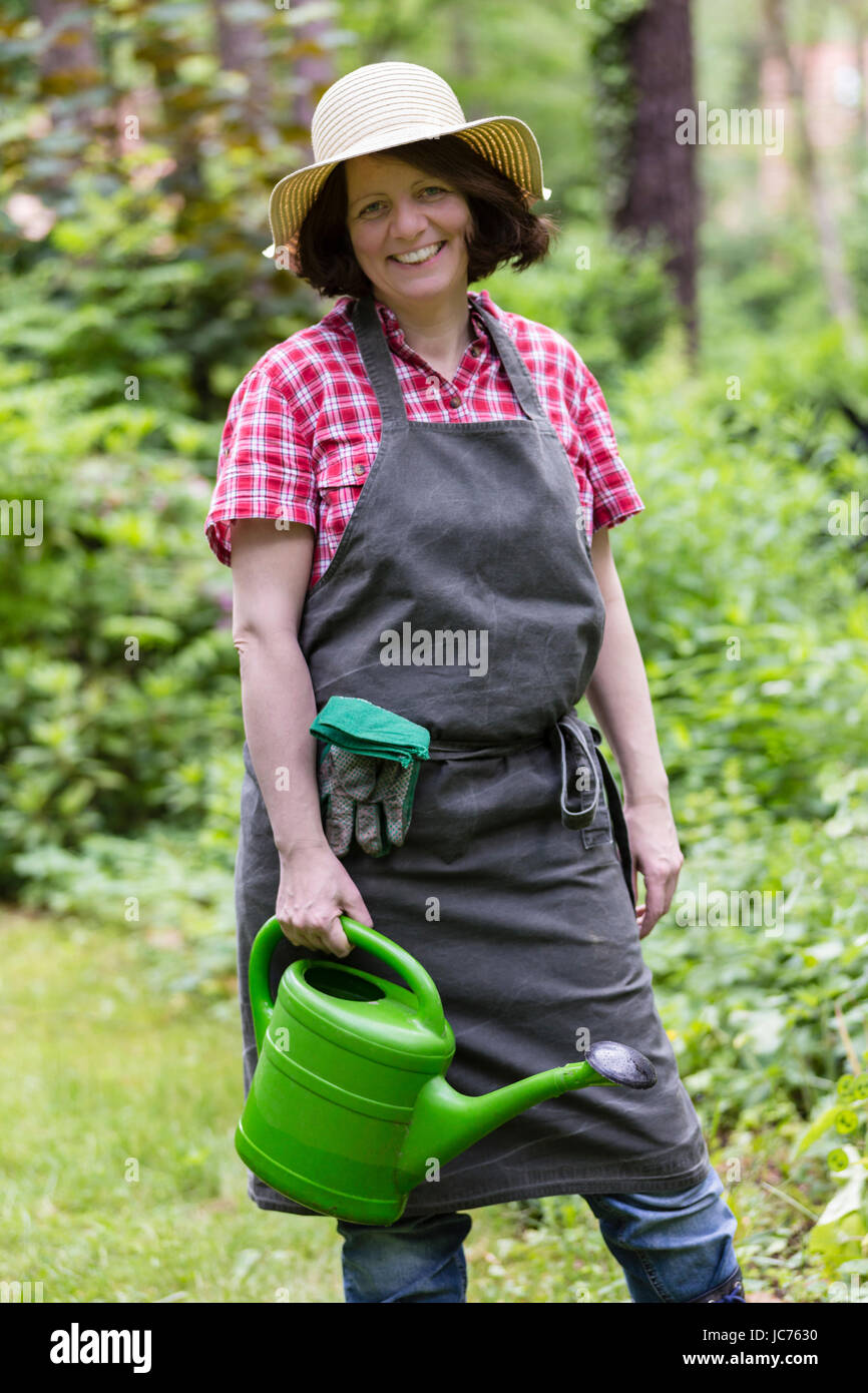 Gärtnerin mit Giesskanne, Sonnenhut und Schürze, gardener with watering can, sun hat and apron Stock Photo