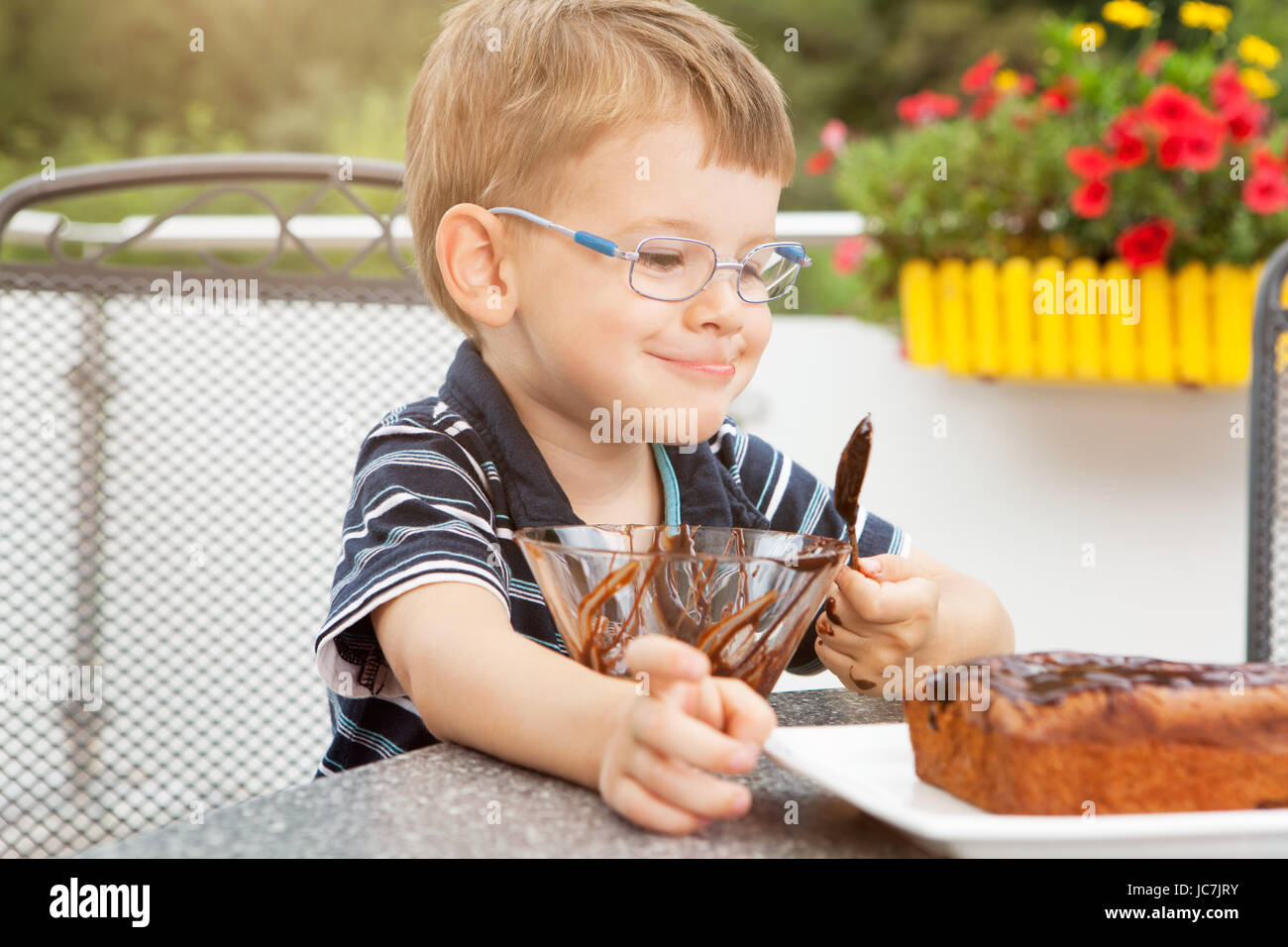 Kleiner Junge beim Schokoladenkuchen verzieren Stock Photo