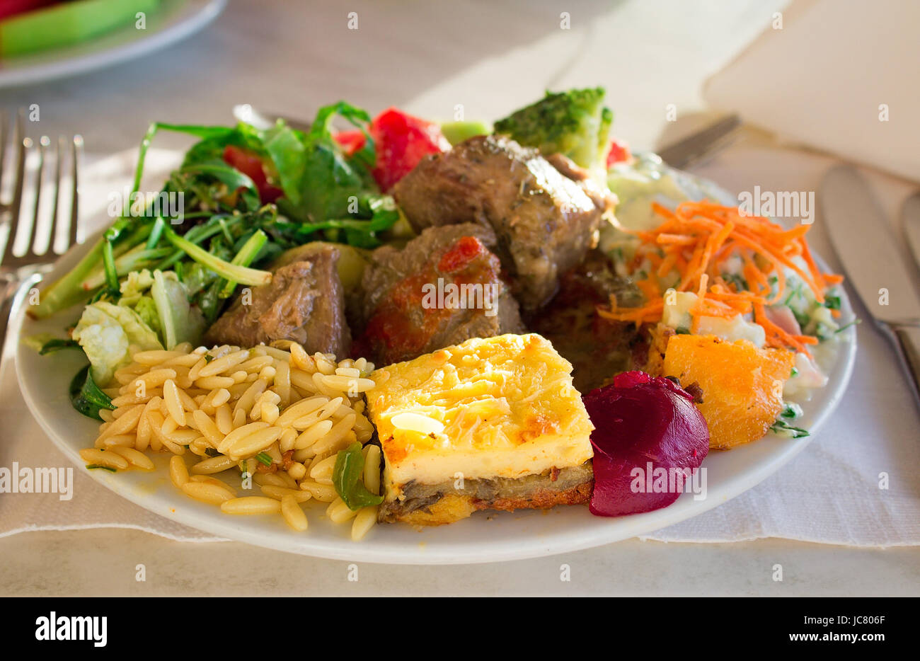 On a cloth of a table the dish with stewed meat, an omelet, vegetables is located. Stock Photo