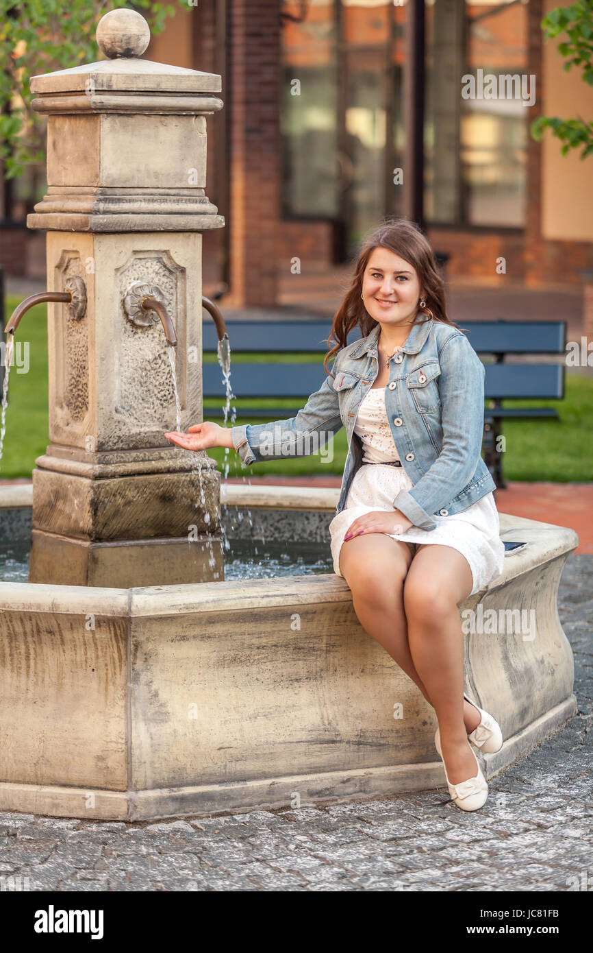 Beautiful smiling woman sitting on side of fountain at old city Stock ...