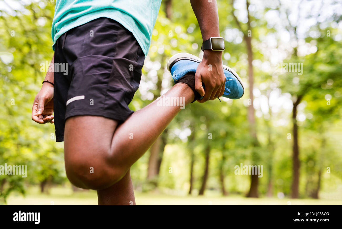 Unrecognizable afro-american man in park stretching legs. Stock Photo