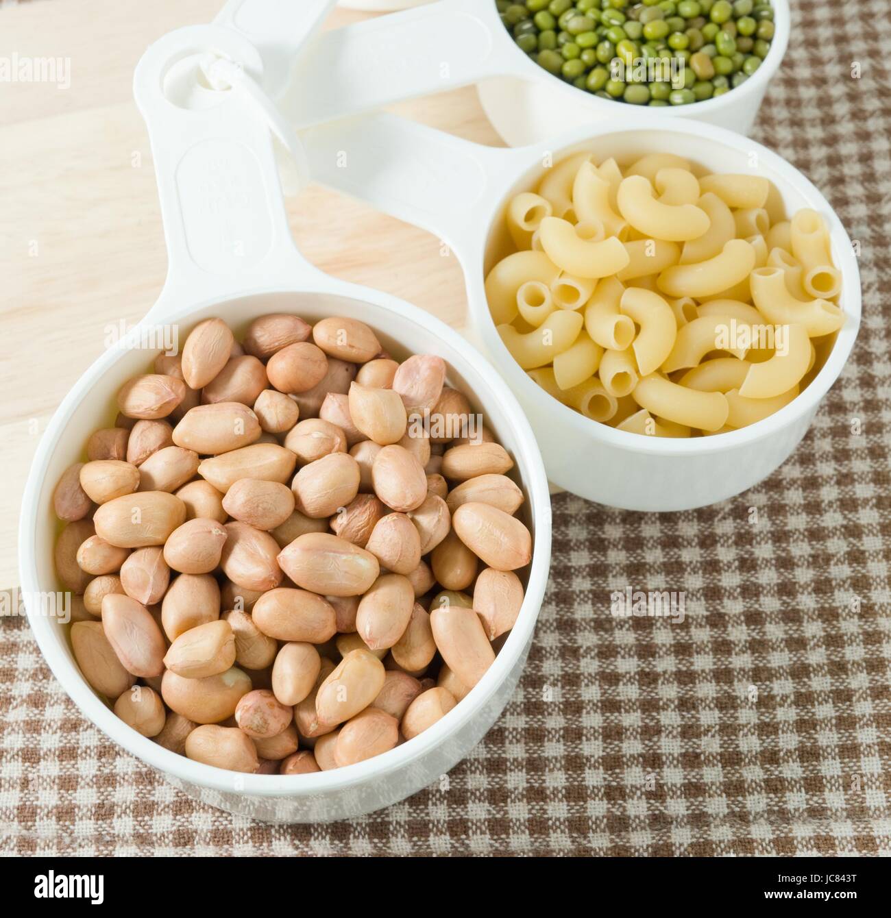 Carbohydrate Foods, Raw Pasta, Rice, Peanuts and Mung Beans in Plastic Measuring Cups. Stock Photo