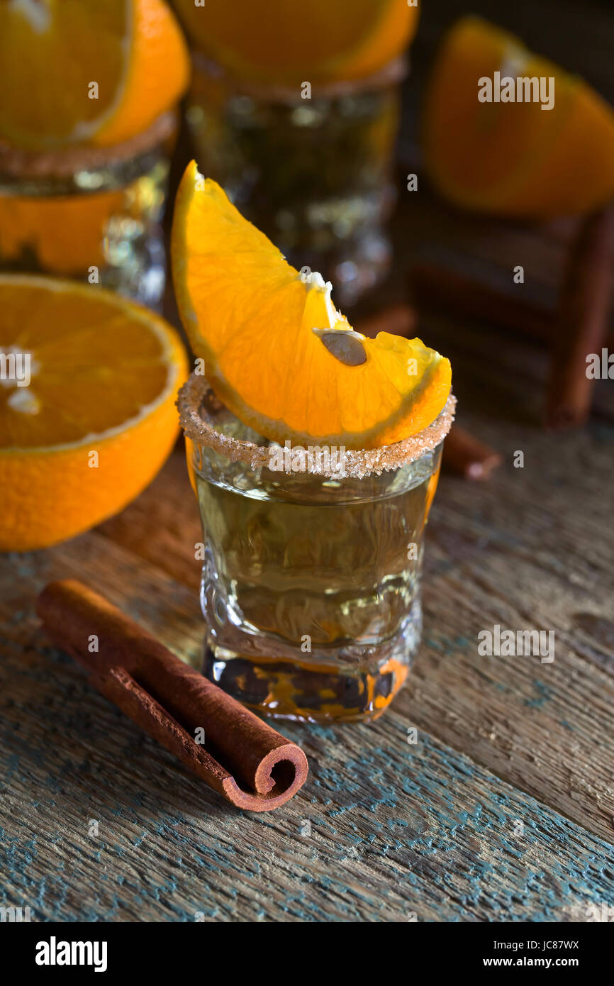 Gold tequila with orange and cinnamon on old wooden table Stock Photo