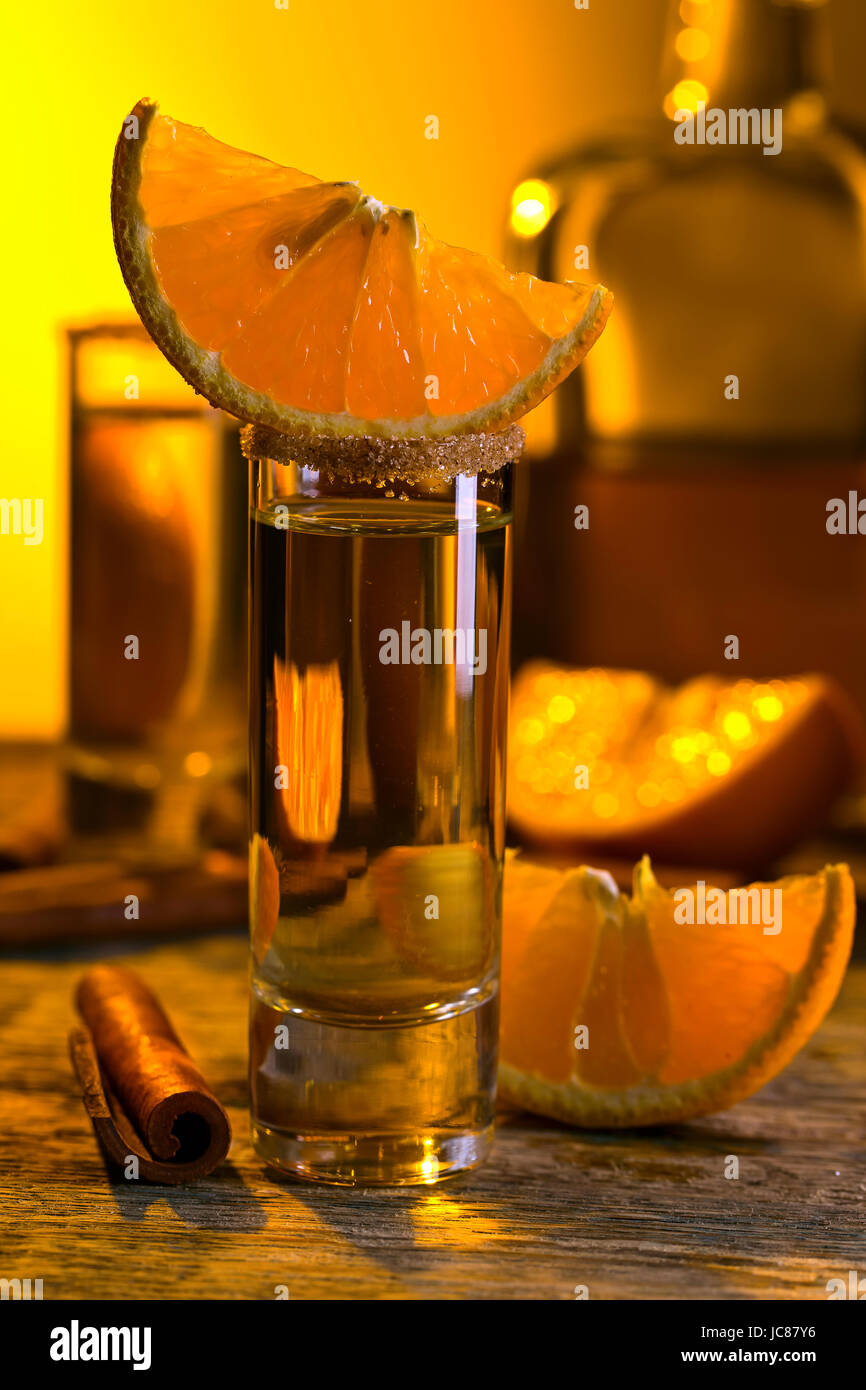 Gold tequila with orange and cinnamon on old wooden table Stock Photo