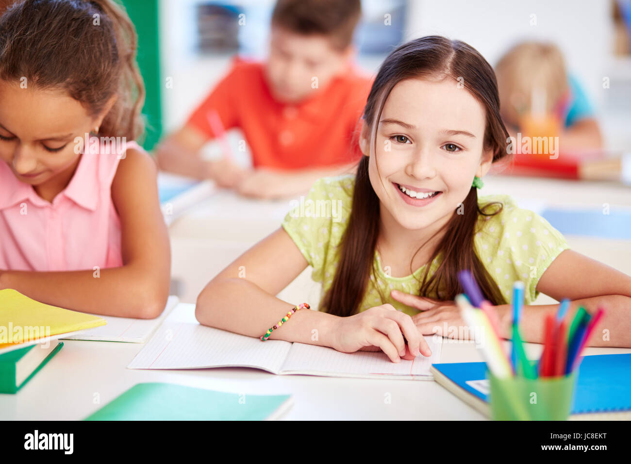 Happy little girl looking at camera at lesson with her friend near by ...