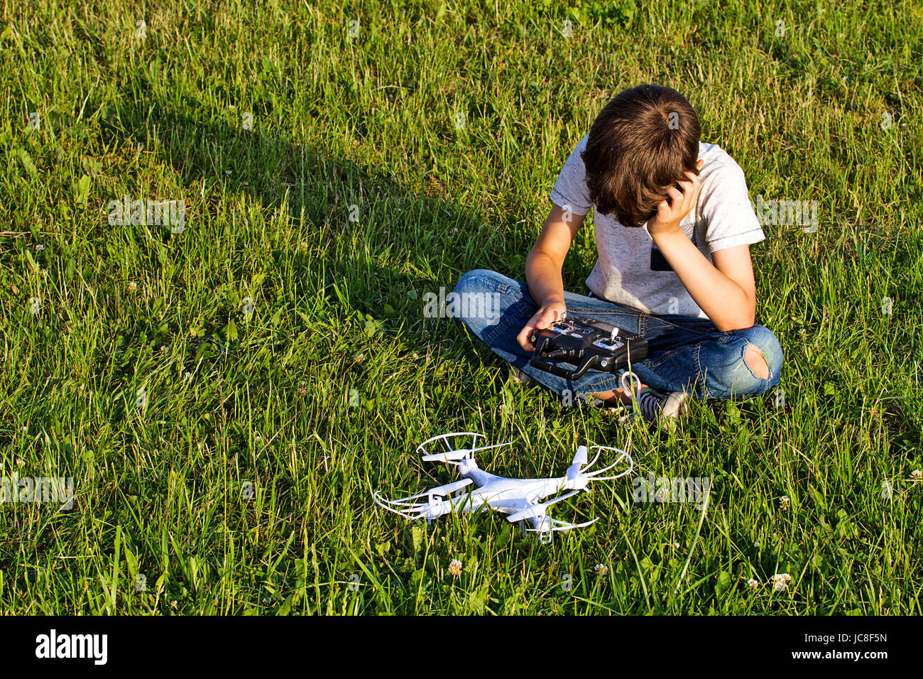 Little boy sitting on the grass with drone and remote controller Stock ...