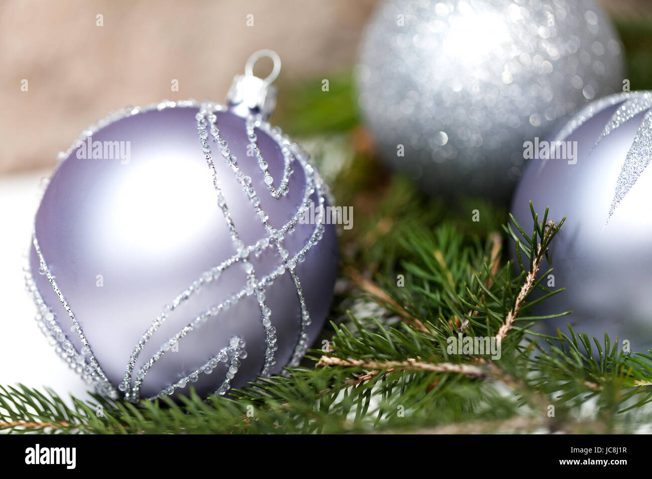 Silberne Christbaumkugeln in grünen Tannenzweigen mit weißem glänzenden