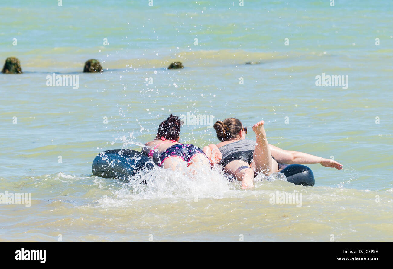 A couple of young women having fun in the sea on a hot day in Summer in June 2017 in England, UK. Stock Photo