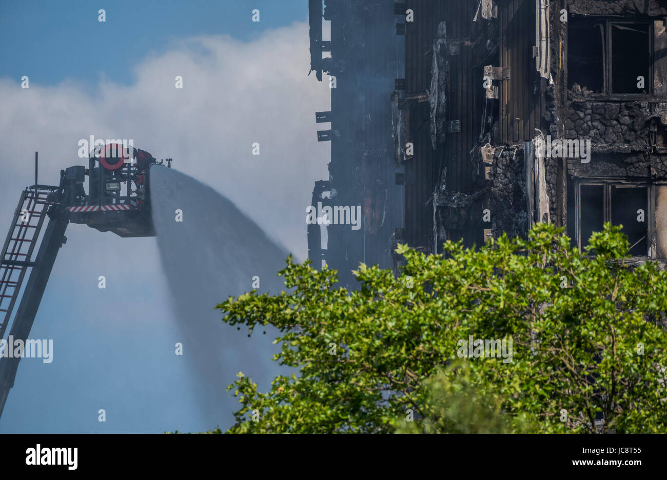 London, UK. 14th June, 2017. The fire service water jet hoses down the building but only reaches about half way up. Grenfell Tower - The charred remains of the tower block that caught fire last night in North Kensington near Latimer Road tube station. London 14 June 2017. Credit: Guy Bell/Alamy Live News Stock Photo