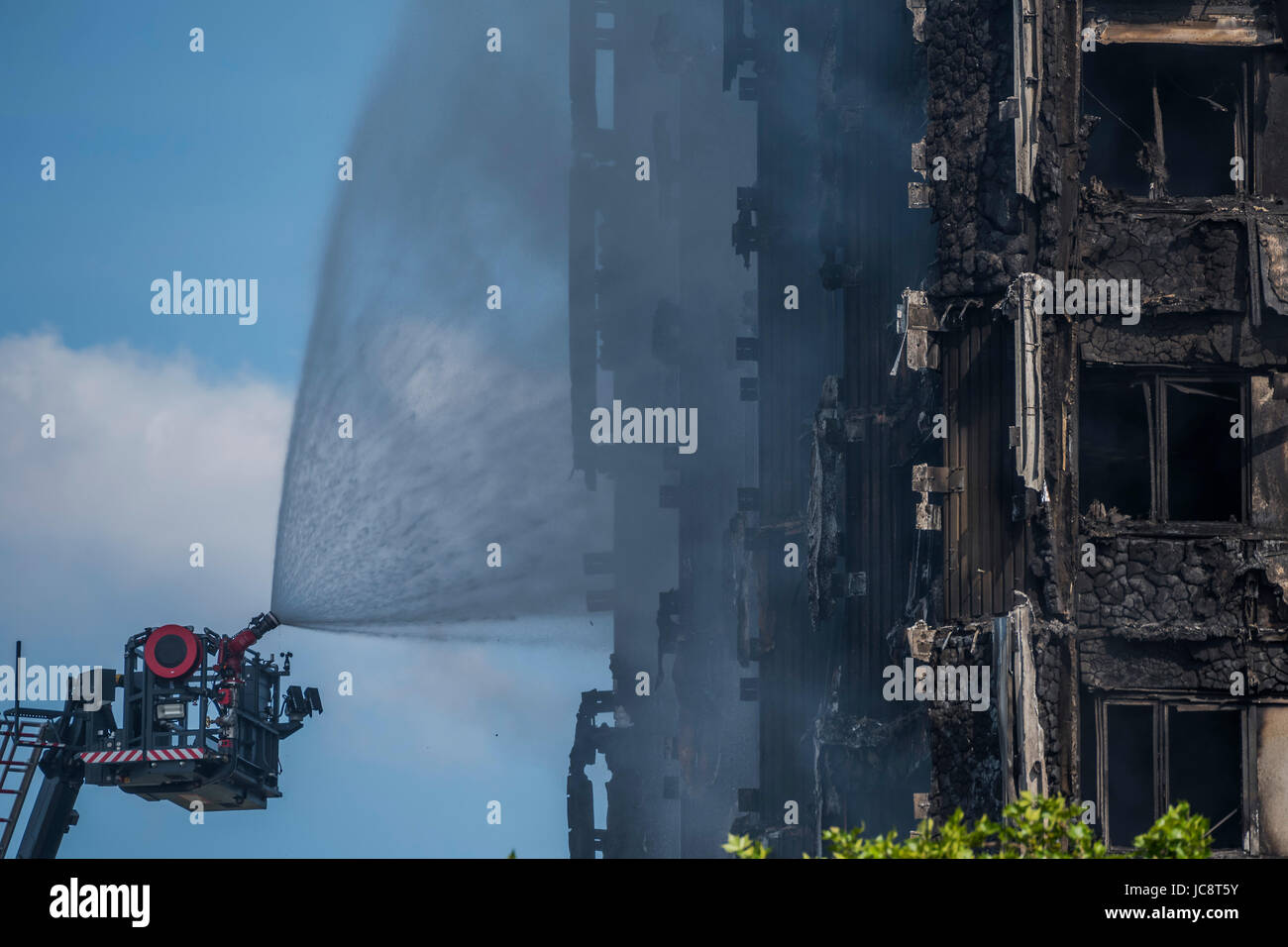 London, UK. 14th June, 2017. The fire service water jet hoses down the building but only reaches about half way up. Grenfell Tower - The charred remains of the tower block that caught fire last night in North Kensington near Latimer Road tube station. London 14 June 2017. Credit: Guy Bell/Alamy Live News Stock Photo