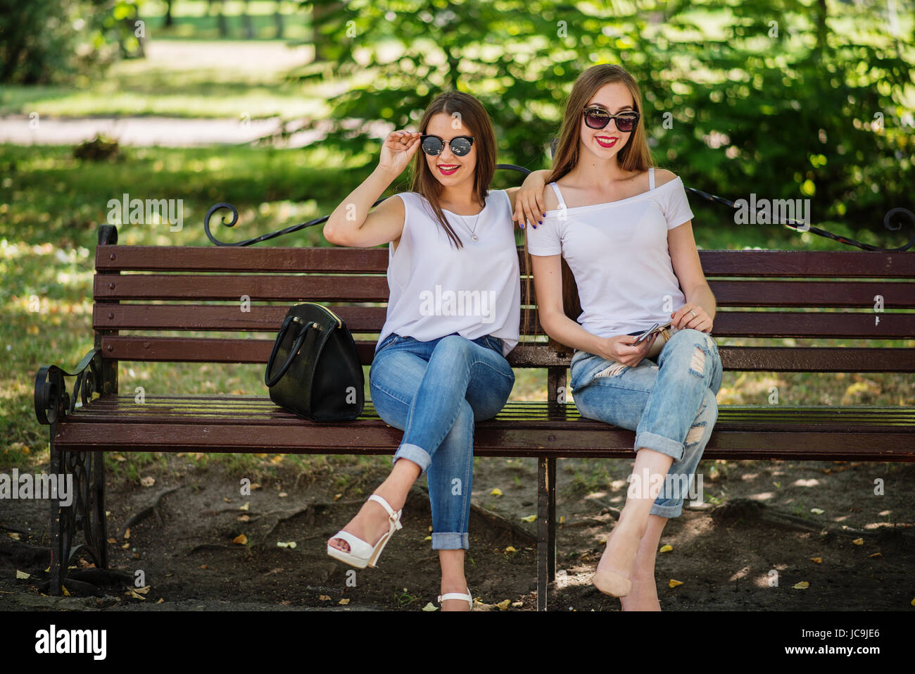Two fabulous girls sitting on the bench in the park Stock Photo - Alamy