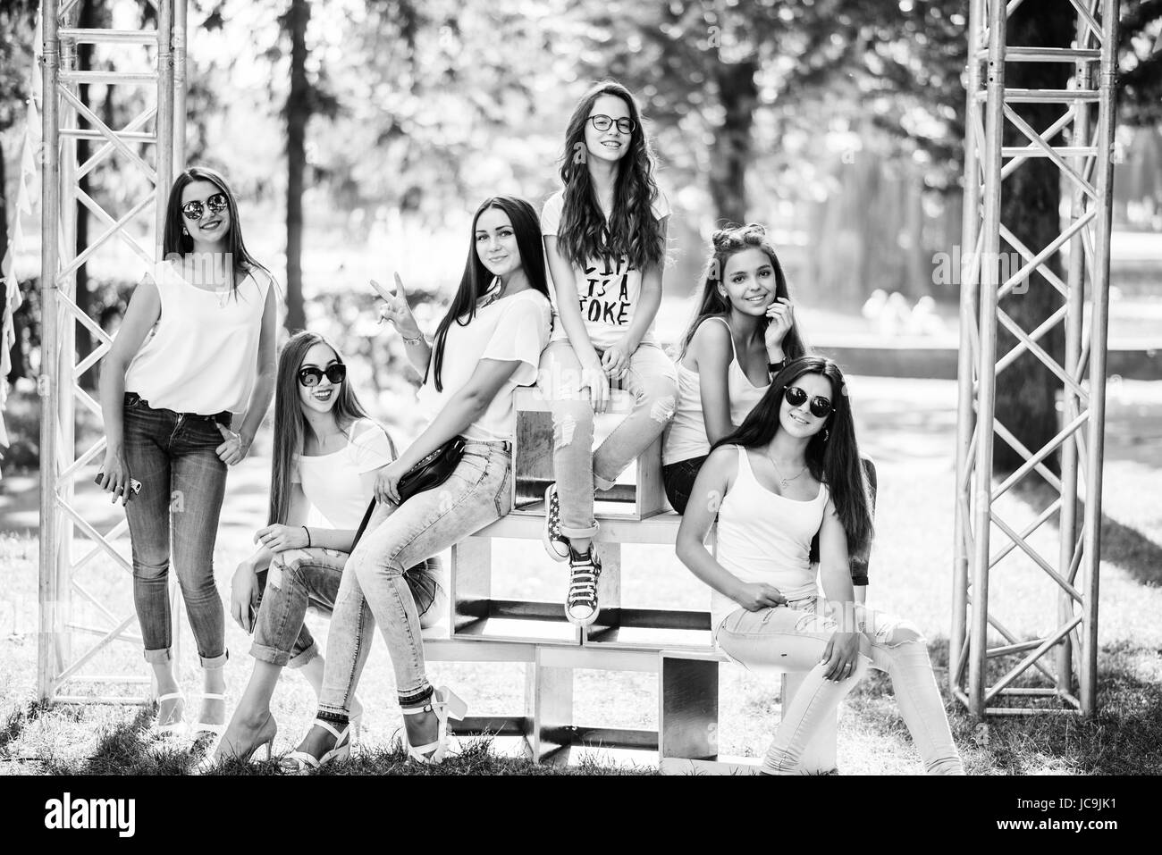 Six wonderful model girls posing on wooden boxes in the park on a sunny day. Black and white photo. Stock Photo