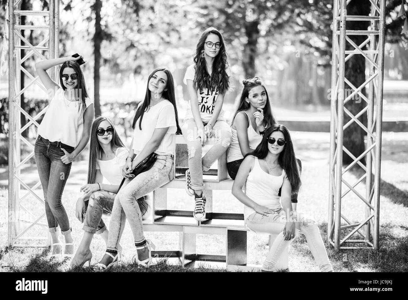 Six wonderful model girls posing on wooden boxes in the park on a sunny day. Black and white photo. Stock Photo