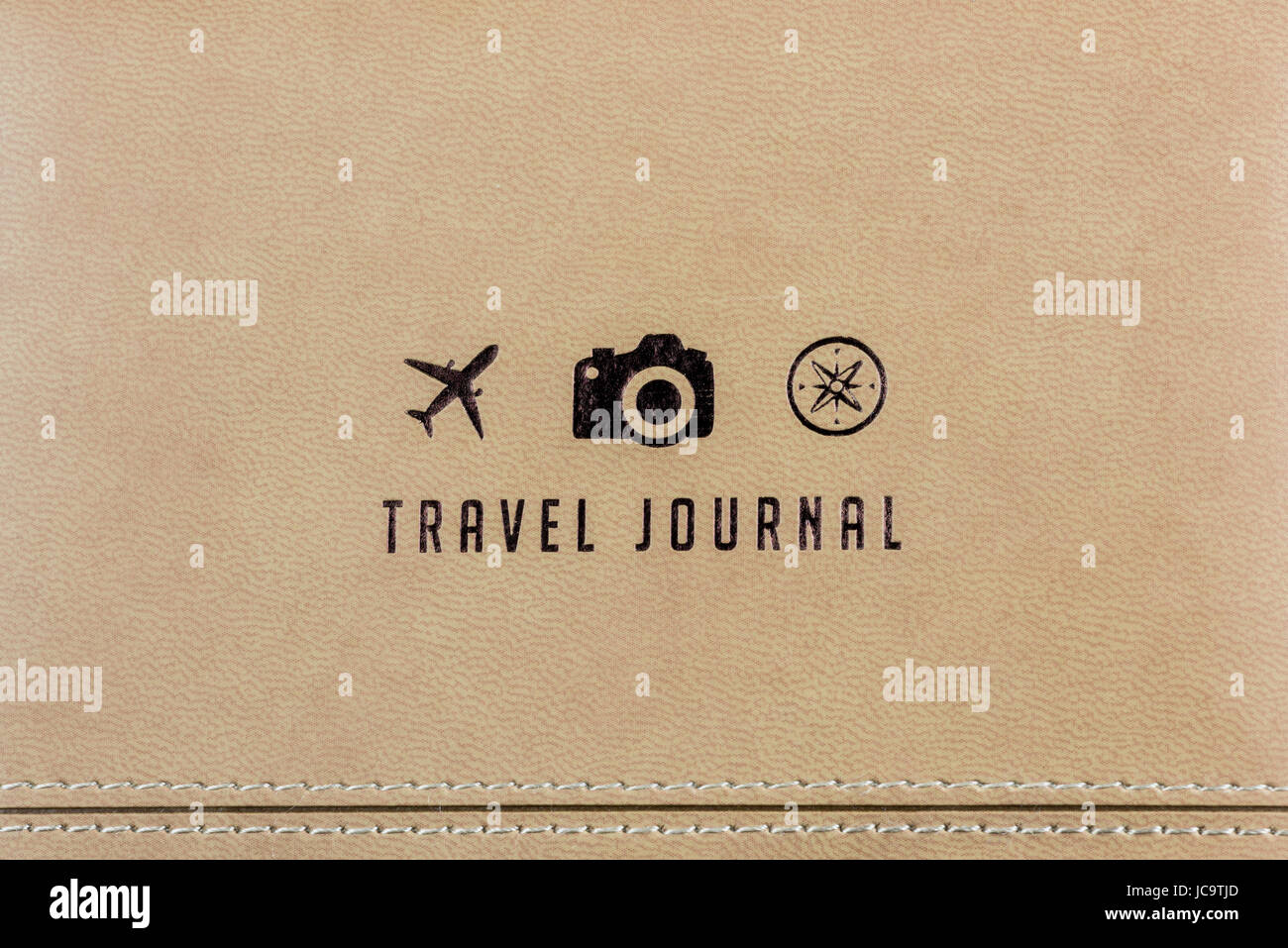 Close-up of a Travel Journal cover with 3 small logos (a plane, a camera and a compass) and an ancient map at background. Travel concept Stock Photo