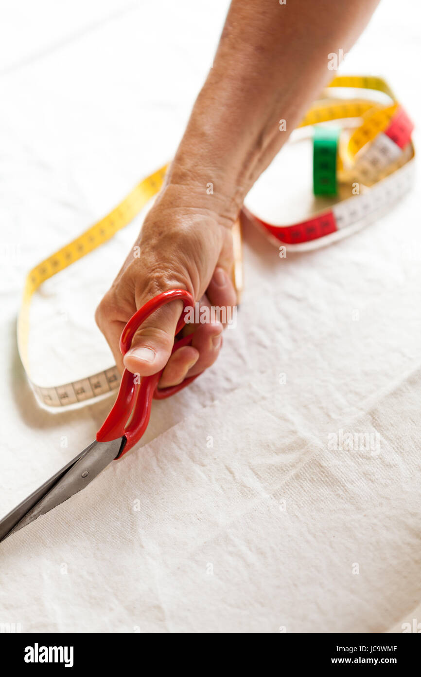 Hände mit Messband schere und Stift beim abmessen von Stoff für die Schneiderei Textil als Nahaufnahme Stock Photo