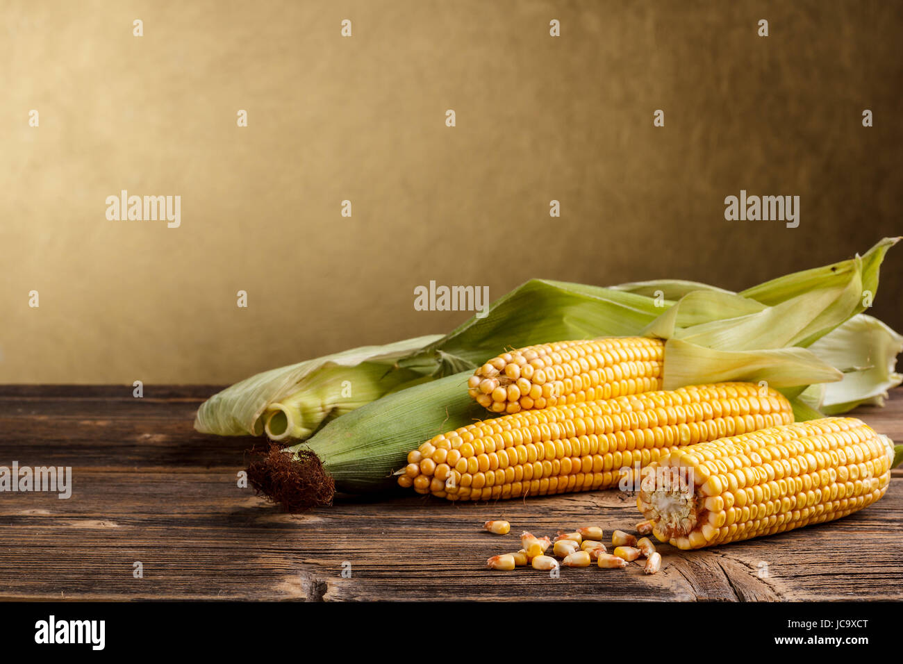 Corn cob and green leaves on rustic wooden table Stock Photo - Alamy