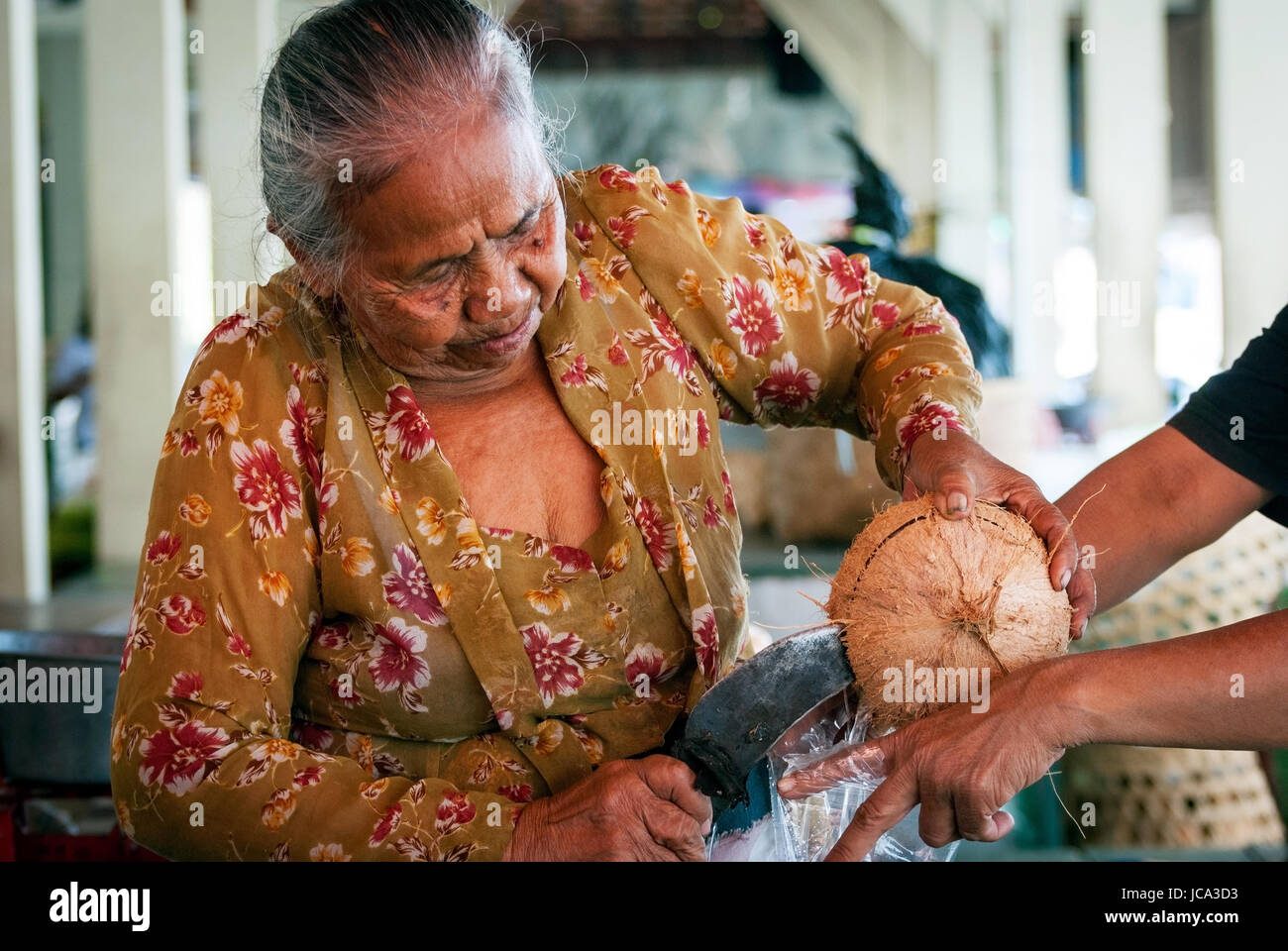 YOGYAKARTA, INDONESIA - SEPTEMBER, 15: Old woman opening coconut to serve coconut milk on the local market in Yogyakarta, Indonesia on Septmber 15, 20 Stock Photo