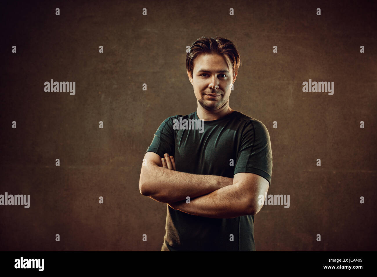 Male positive portrait. On dark stone wall background. Warm colors. Stock Photo