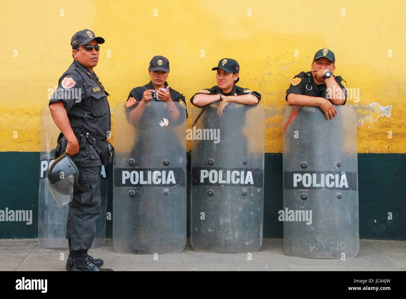 Policemen with riot shields standing by the wall in Lima, Peru. Peruvian National Police is one of the largest police forces in South America. Stock Photo