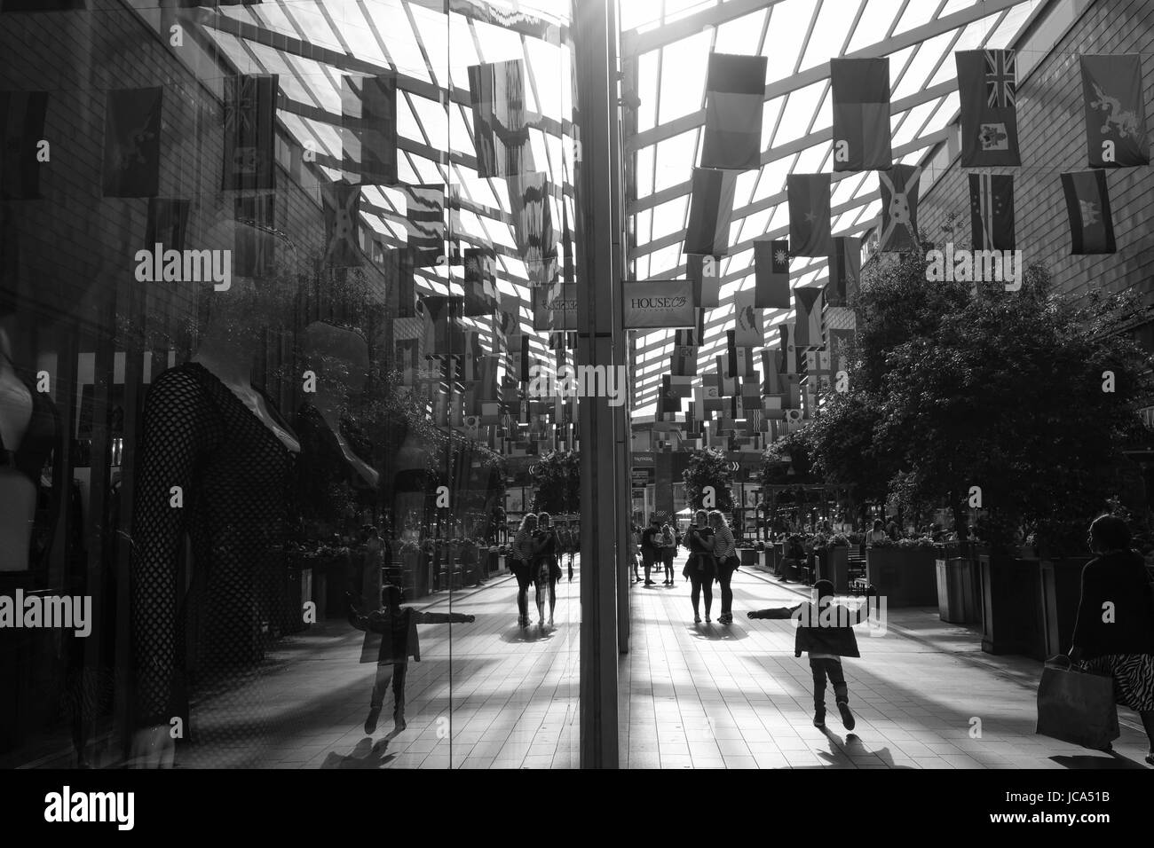 Child is playfully running along the corridor in Westfield Stratford City shopping centre; World flags are hanging above from the ceiling Stock Photo