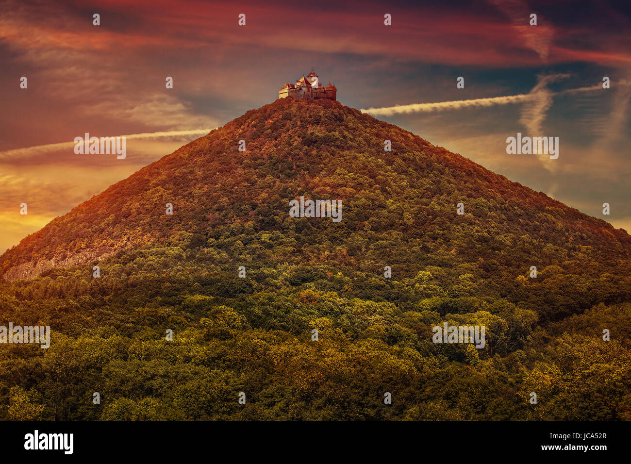 Castle on high mountains top with forest at sunset red colors Stock Photo