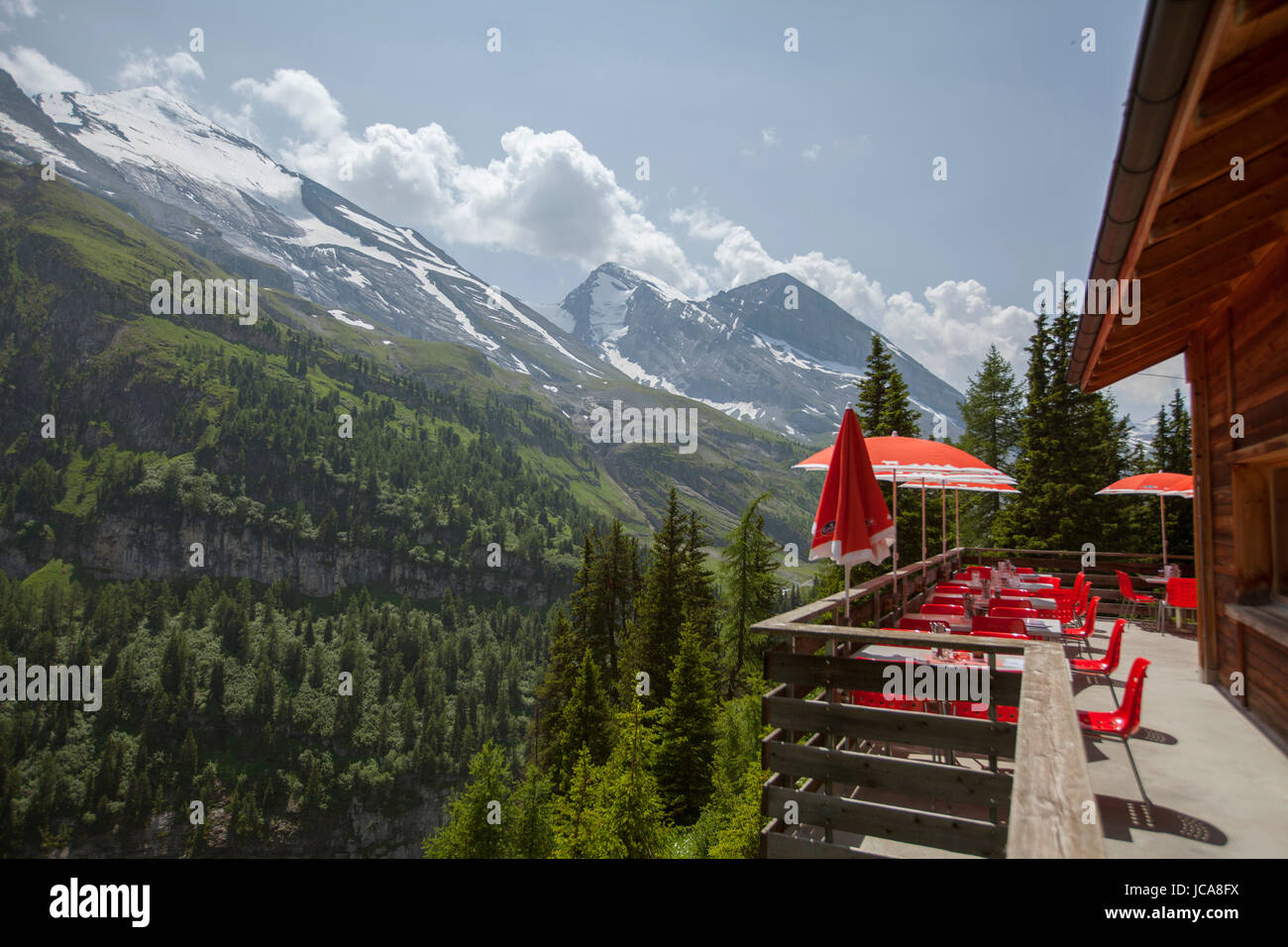 A lodge deck with red umbrellas overlooks the Swiss Alps.  Kandersteg, Switzerland. Stock Photo