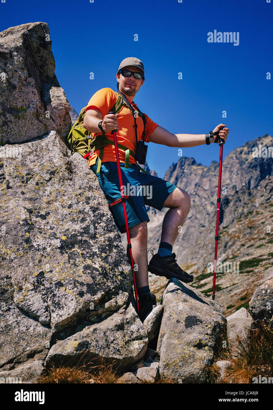 Young man tourist with poles standing at high mountains Stock Photo