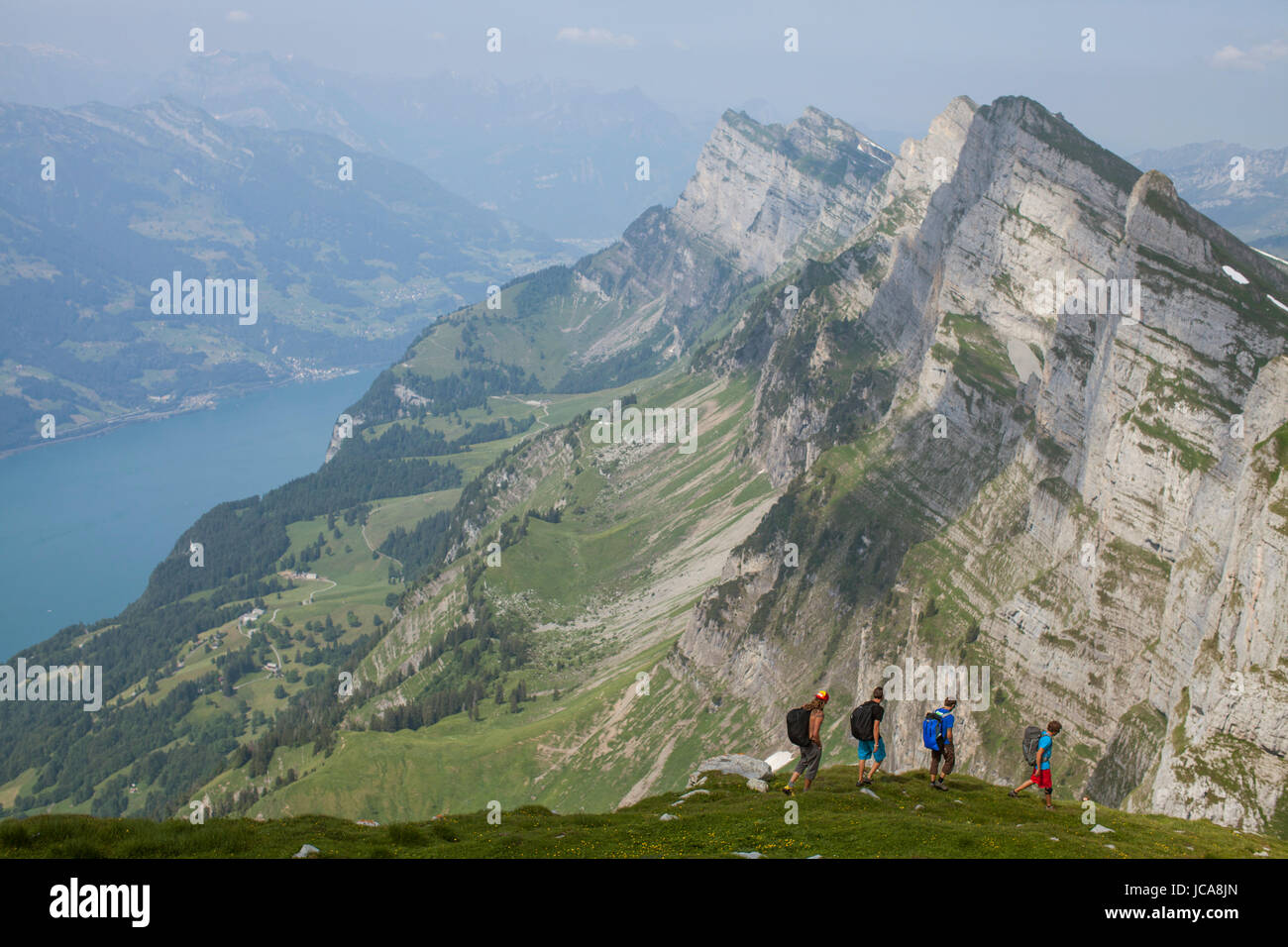 A group of base jumpers hiking in the Alps above Lake Wallen to find their next flight sight.  Toggenburg, Switzerland Stock Photo