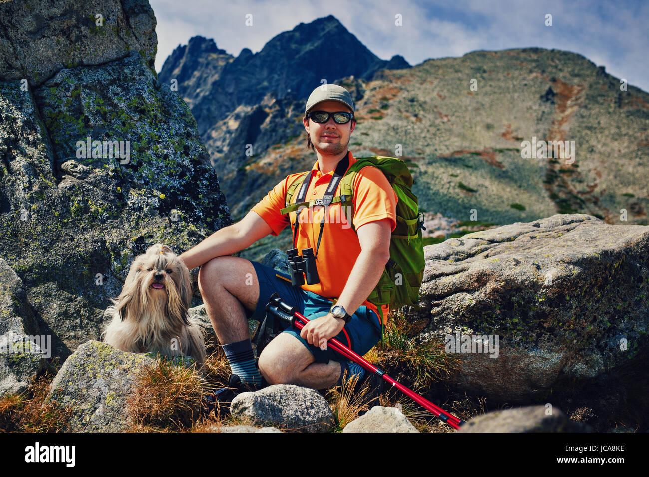 Young man tourist with dog portrait on high mountains background Stock Photo