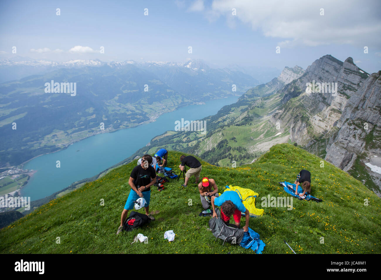 A group of base jumpers preparing to jump the crack in the Swiss Alps above Lake Wallen. Stock Photo