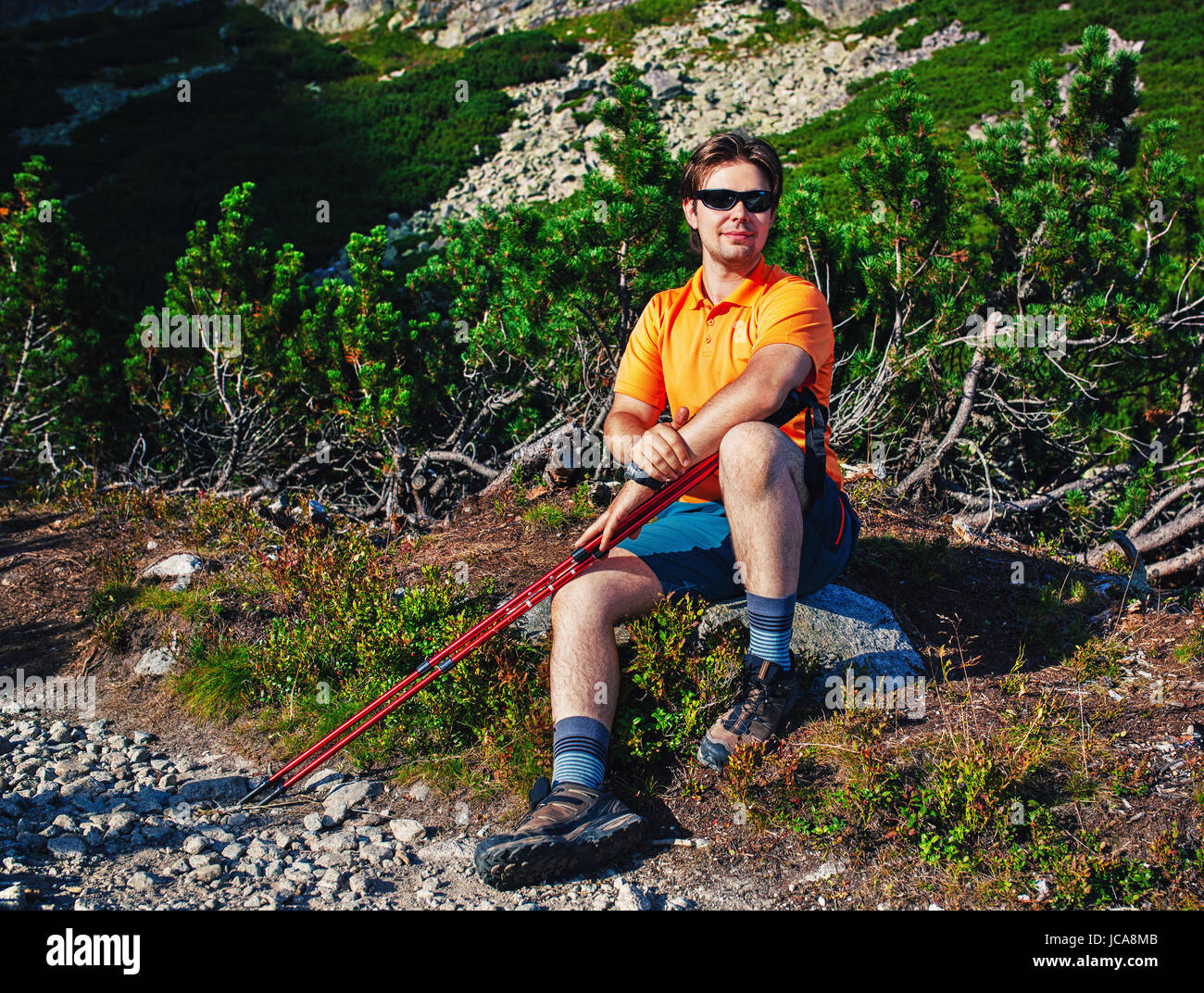 Young man tourist with sunglasses sitting at mountains portrait Stock Photo