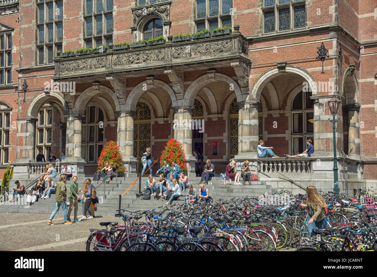 Students sitting on the steps of the main entrance of the RUG University of Groningen in the Netherlands Stock Photo