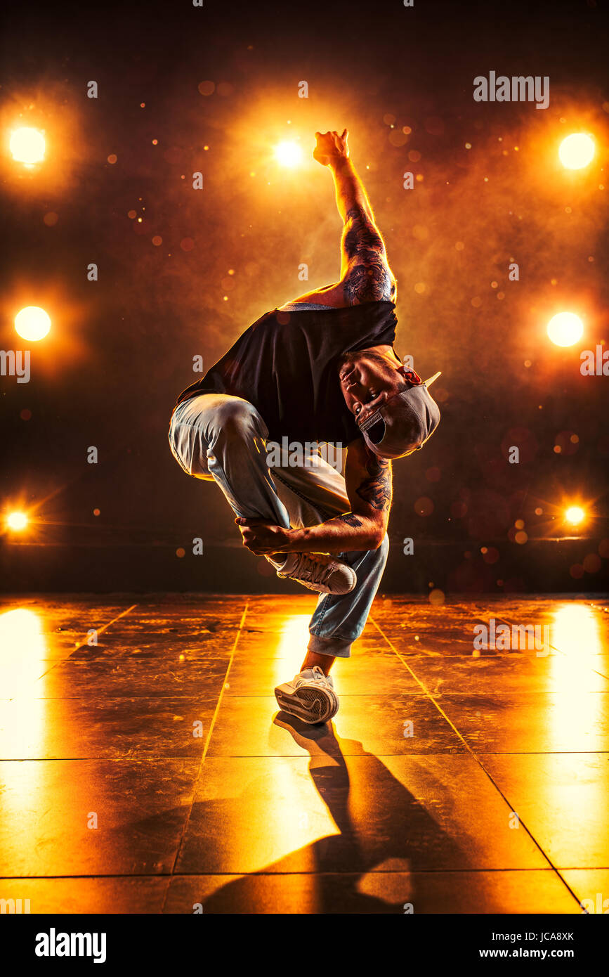 Young man break dancing in club with lights and smoke. Tattoo on body. Stock Photo