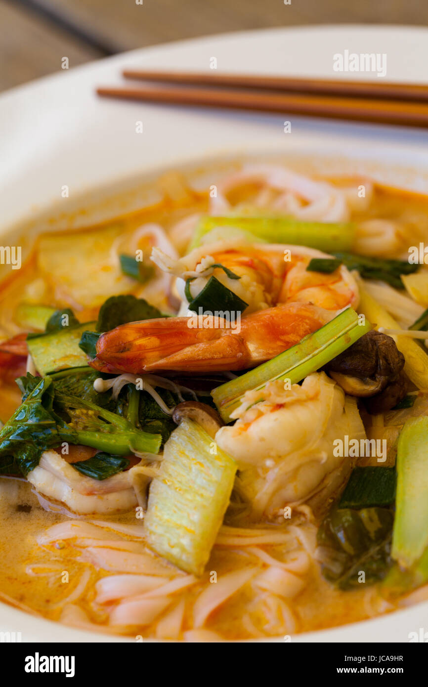 Schale Teller mit frisch zubereiteter Tom Yam Suppe mit Languste und Koriander mit Stäbchen als Nahaufnahme Stock Photo