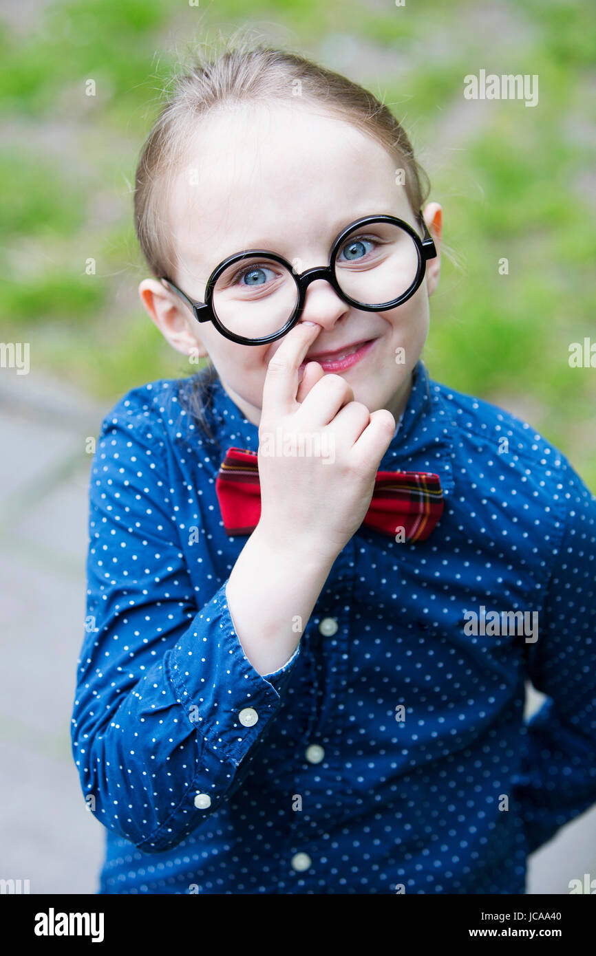 young blond boy with bow tie and big glasses is picking his nose Stock Photo